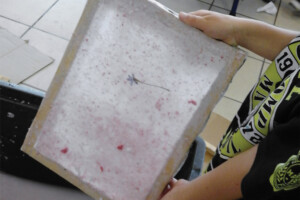 PAPIER RECYCLÉ <br> Cet atelier se fait en petits groupes, les uns déchirent le papier, les autres préparent la pâte à papier, un troisième groupe s’occupe de la passer dans les tamis et de mettre les feuilles à sécher. On peut rajouter des fleurs pour décorer ou des graines pour faire des cartes à planter.